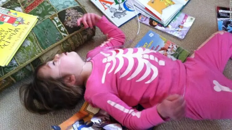 A child in pink clothing lying beside books.