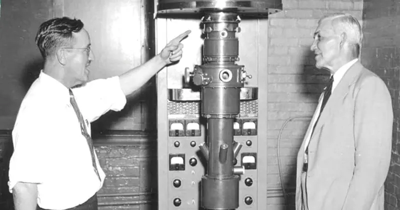 Two researchers standing beside laboratory equipment in a black-and-white photograph.