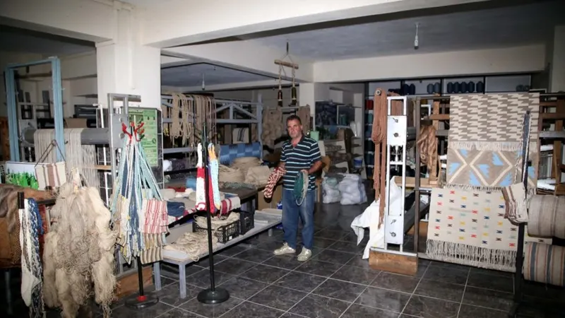 Person working in a workshop with weaving looms.