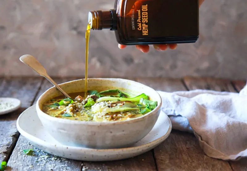 Oil being poured from a bottle into a bowl of food.