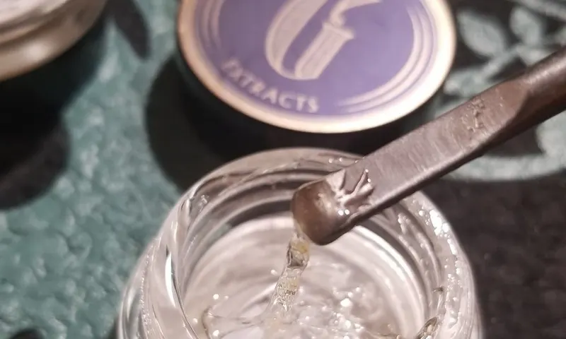 An herbal mixture being scooped from a container with a metal spoon.