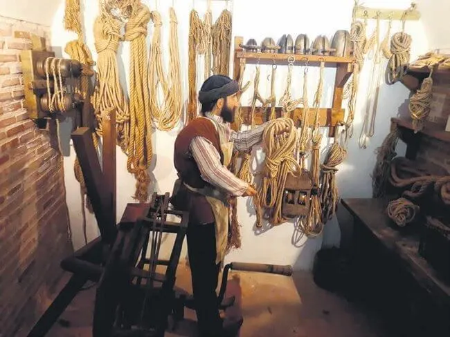 A person working in a workshop filled with ropes and cords.