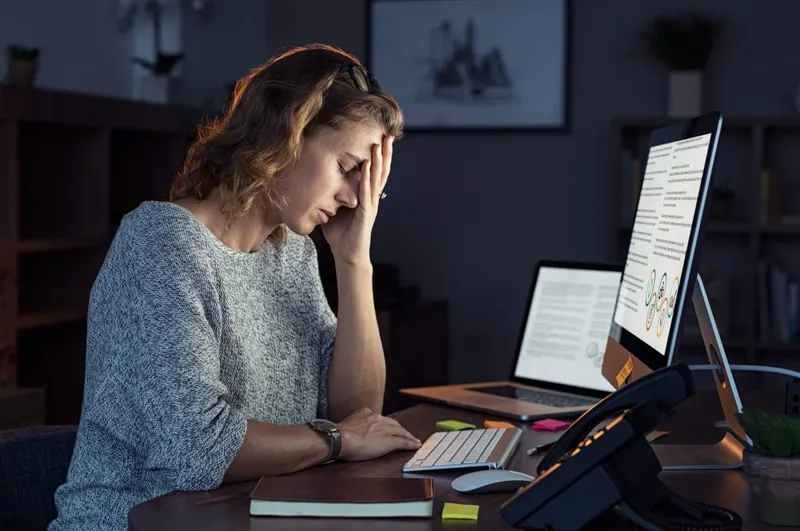 A person supporting their head with a hand while looking at a computer screen.
